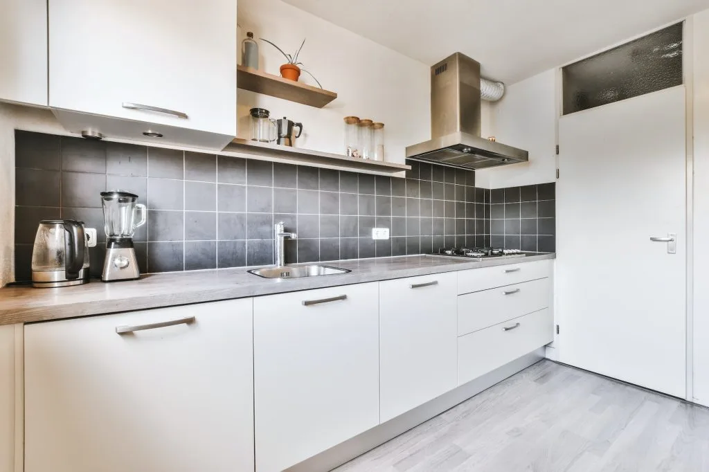 The interior of a charming kitchen with a black tiled wall